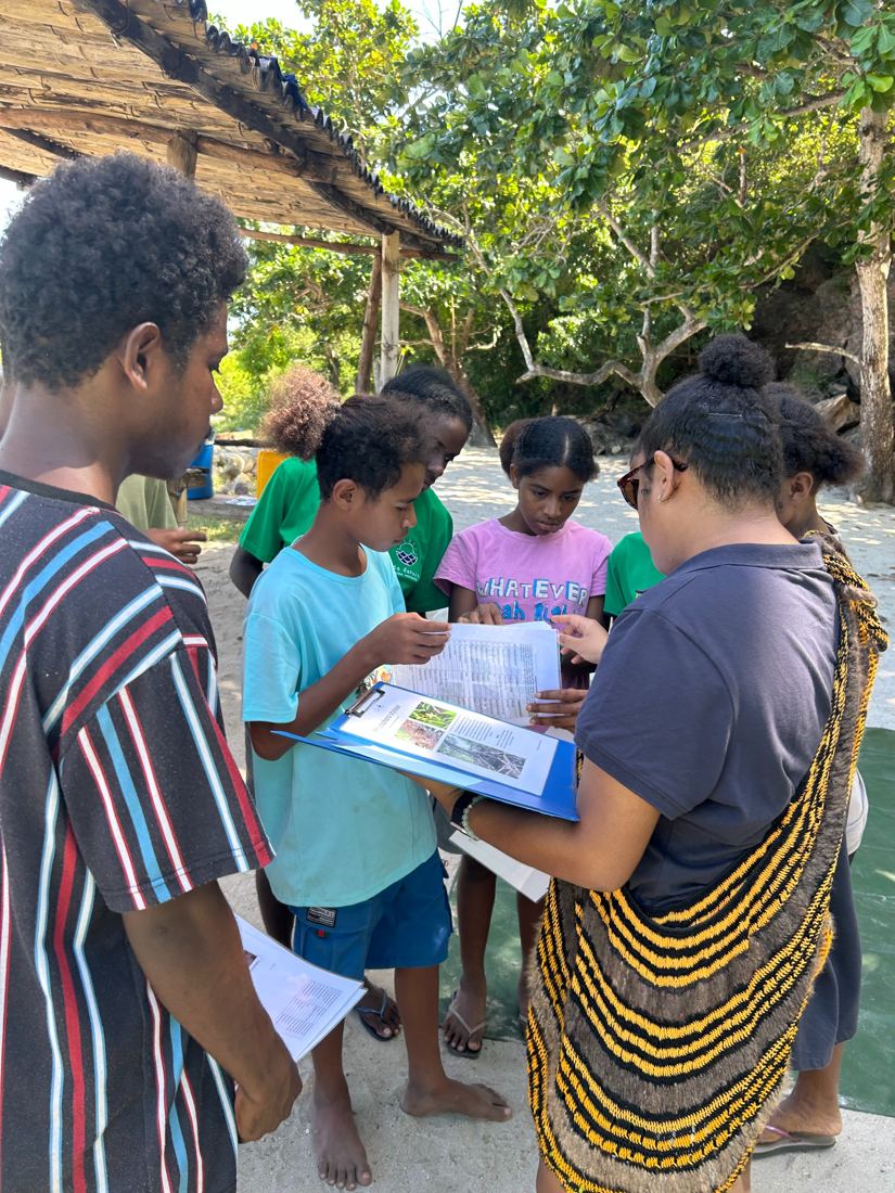 An Eda Davara guide helping students use a species identification key on a clipboard