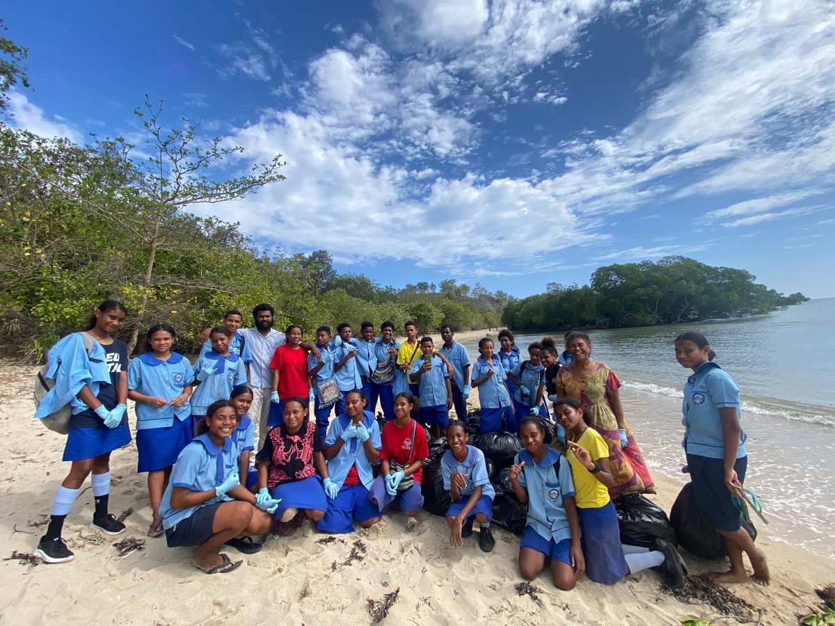 EcoRangers in school uniform on Tomisini Beach with bags of rubbish they collected