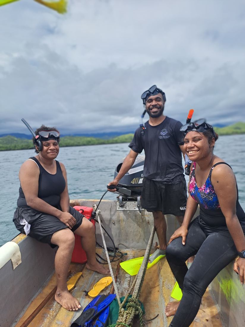 Three EcoScholars with masks and snorkels in a dinghy after a reef survey