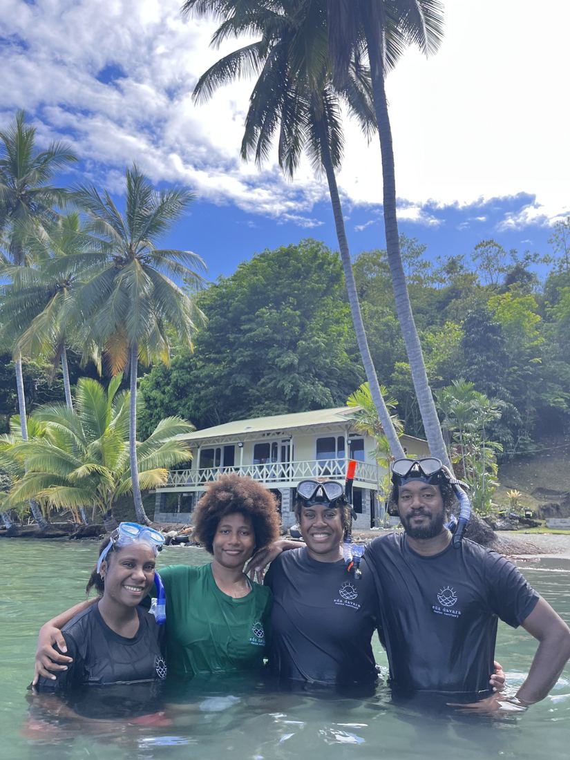 Four team members in snorkel masks standing in the water after a reef survey