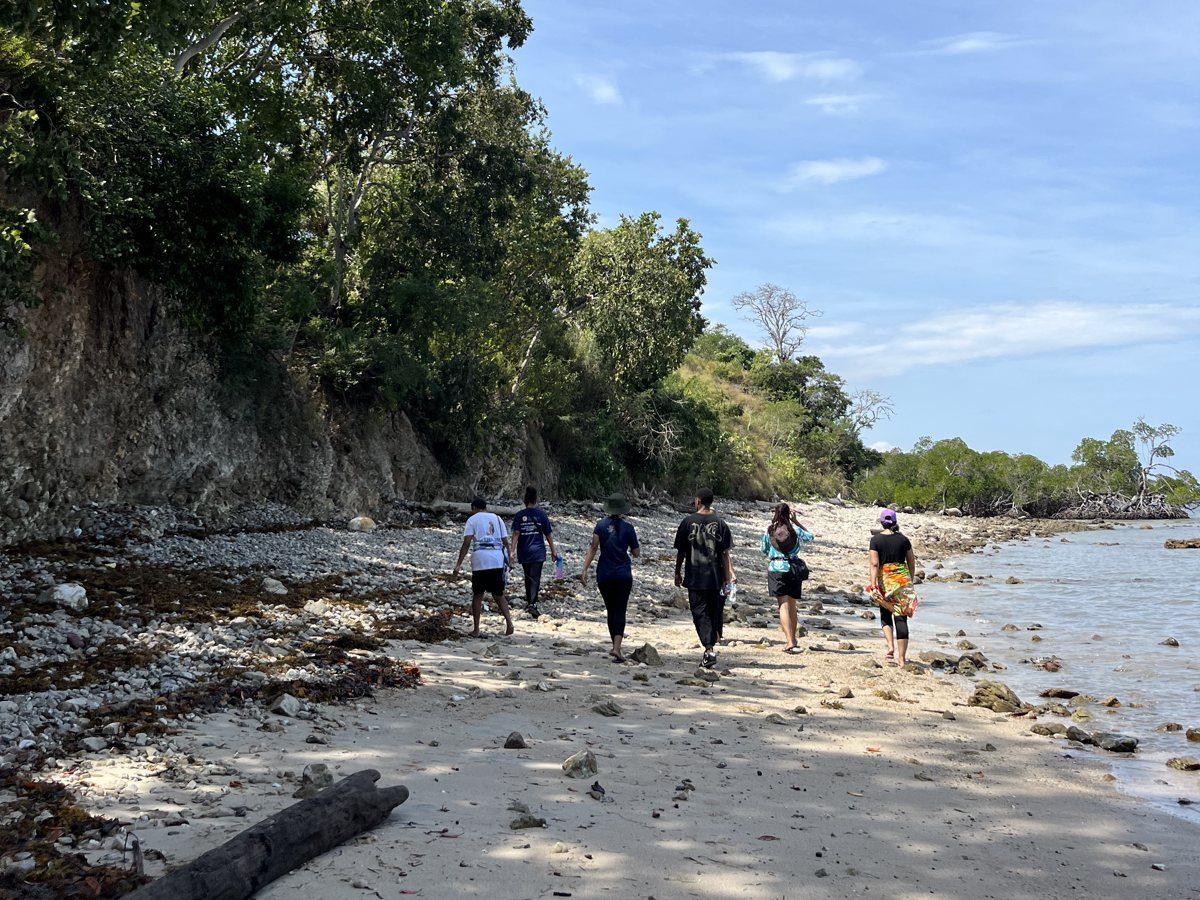 A tour group walking along the Kohua shoreline below the trees