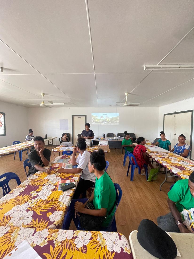 Community members at tables during an Eda Davara mangrove nursery presentation