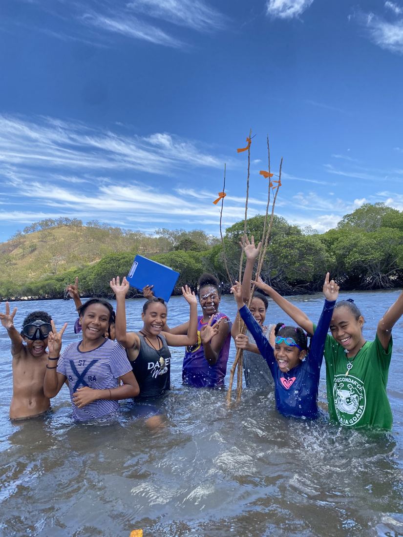 Children cheering in the shallows with transect poles after a seagrass survey